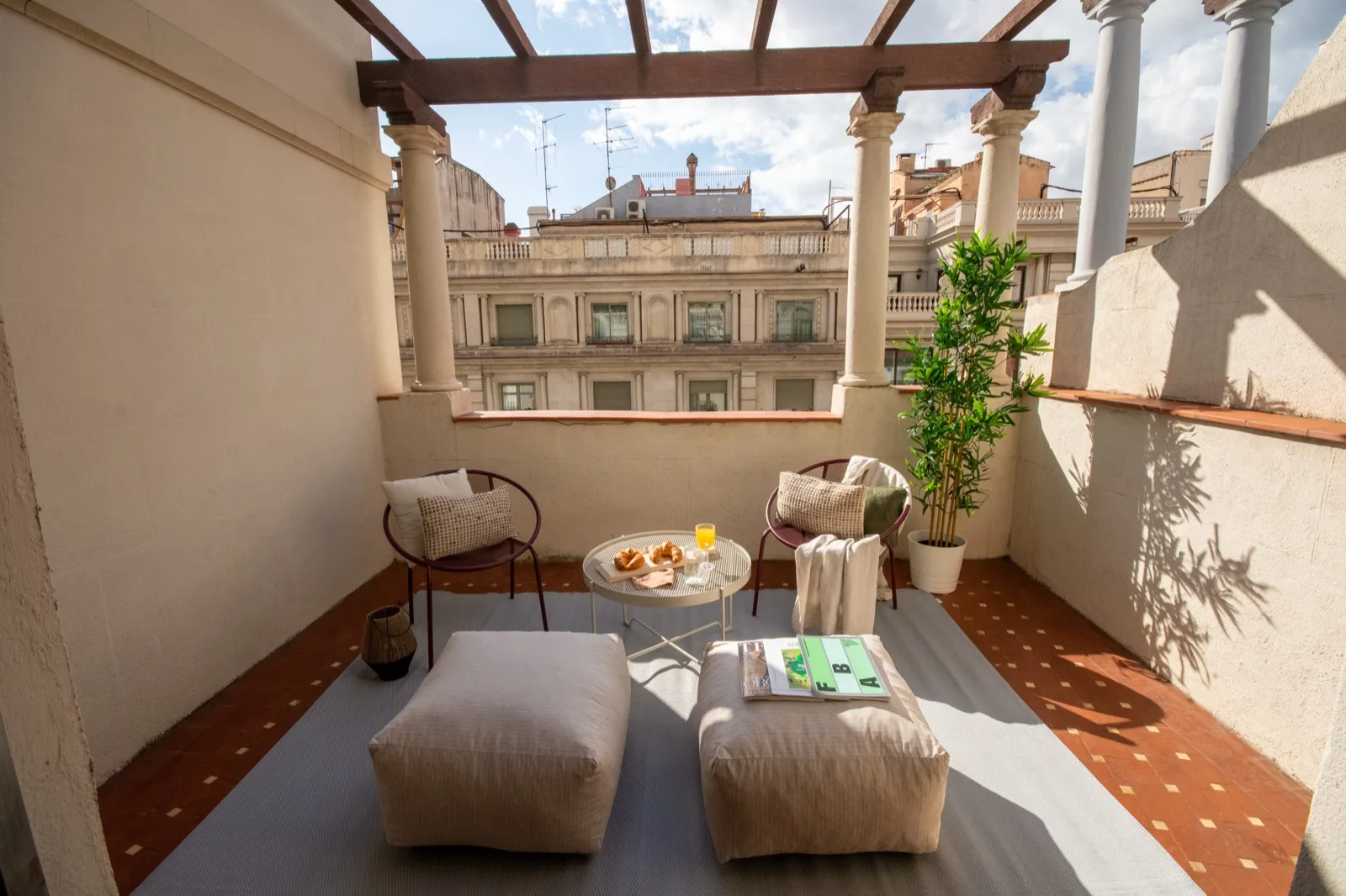 Private terrace of a Viver apartment with lounge seating and Barcelona rooftop views.