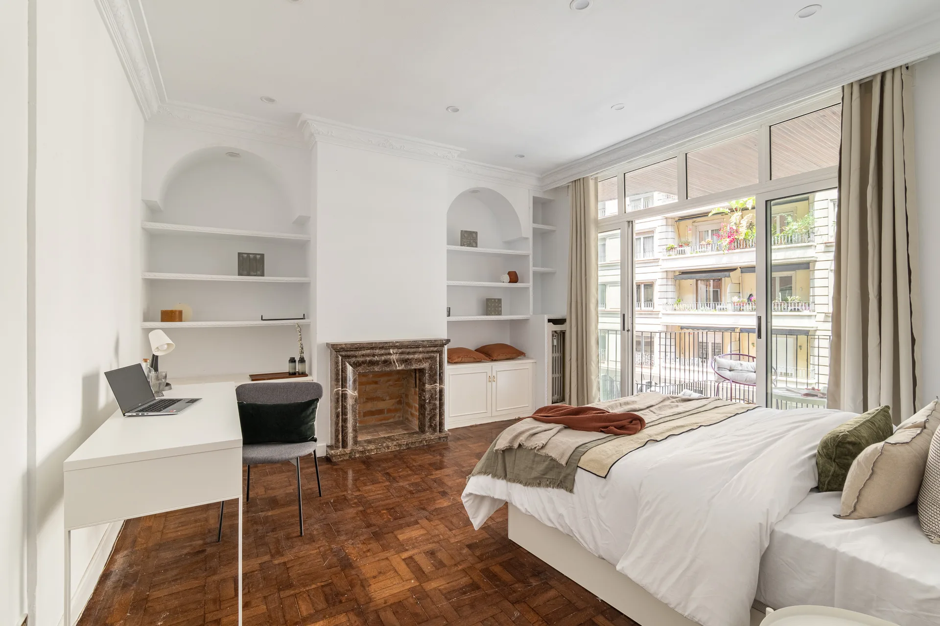 Bedroom at Passeig de Gràcia 88, Barcelona, with a marble fireplace and a balcony over modernist façades.